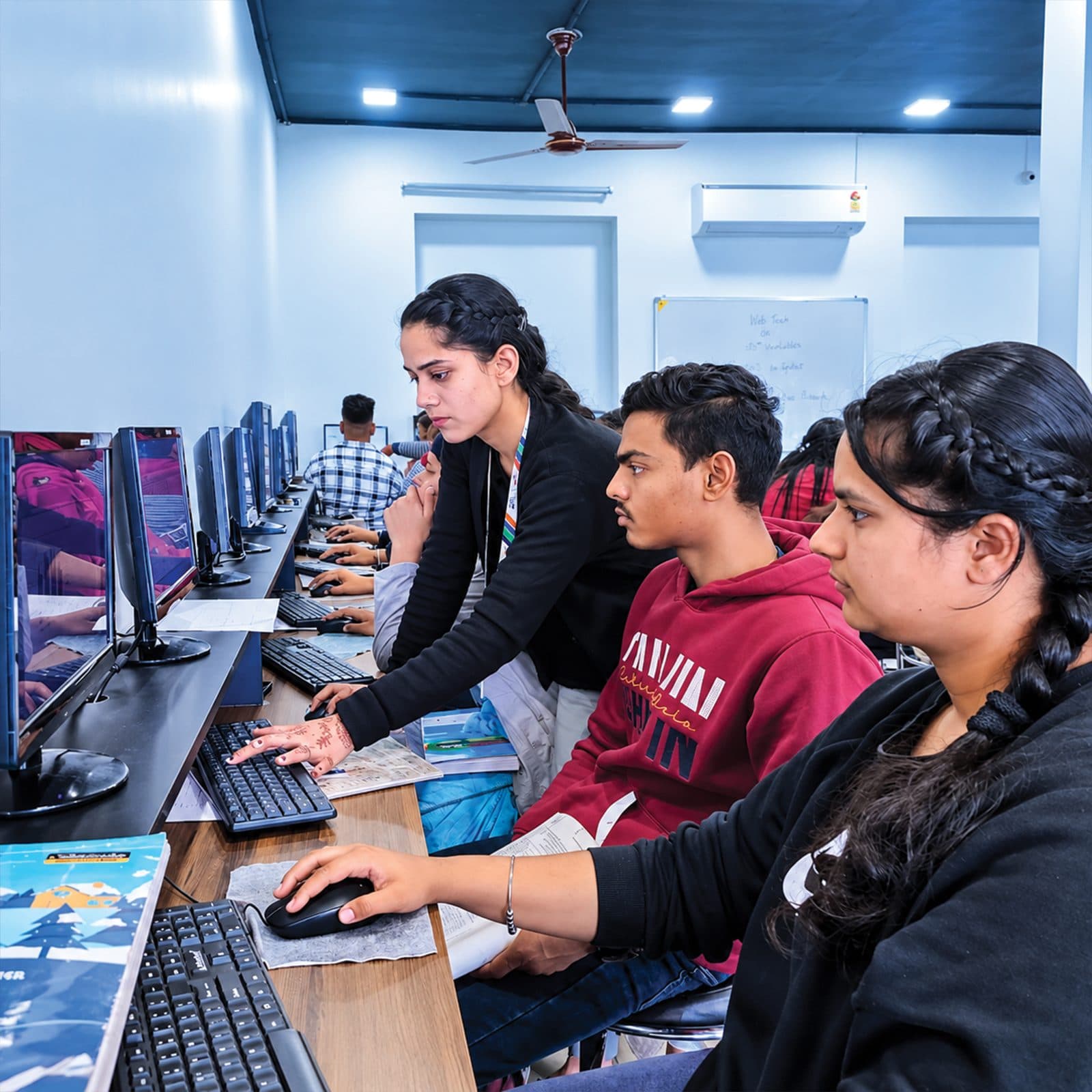 Trainer guiding students working at computers in a lab